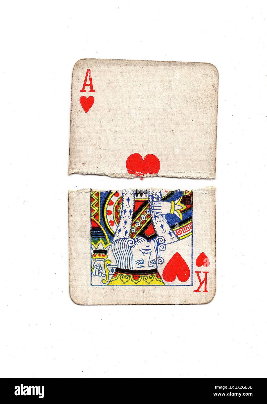 Zerrissene Hälften alter Spielkarten, die einen König und ein Ass der Herzen auf weißem Hintergrund zeigen. Stockfoto