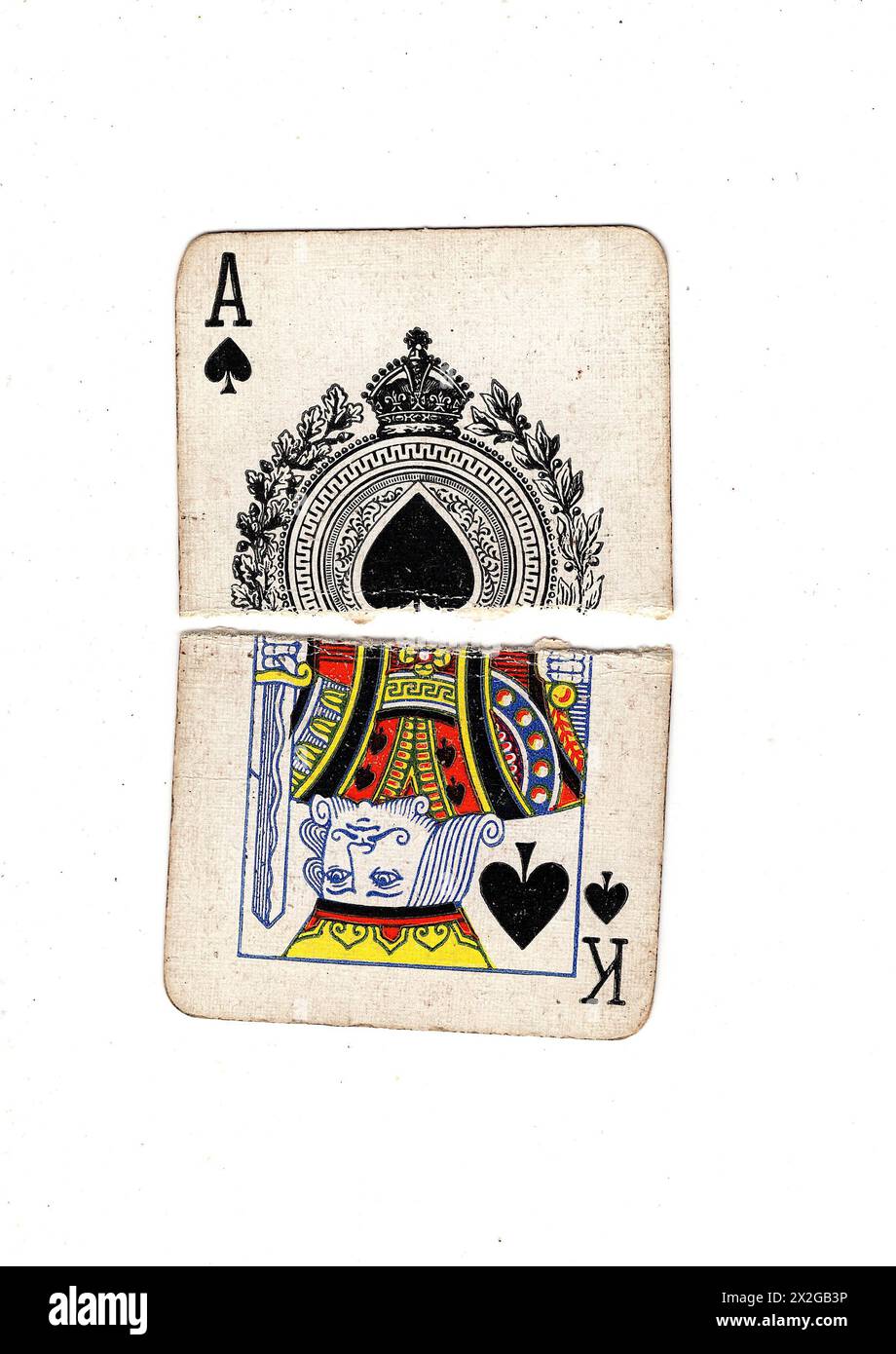 Zerrissene Hälften alter Spielkarten, die einen König und ein Pik-Ass auf weißem Hintergrund zeigen. Stockfoto