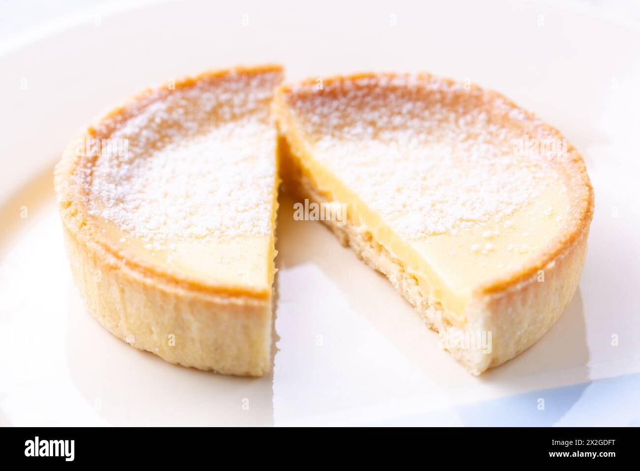 Eine Zitronentorte (Tarte au Citron), in zwei Stücke geschnitten und mit Puderzucker bestäubt Stockfoto