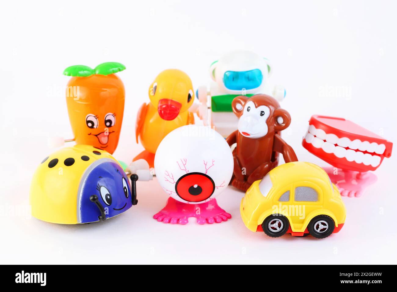 Gruppe von acht kleinen, hellen Uhrwerk-Spielzeugen auf weißem Hintergrund Stockfoto