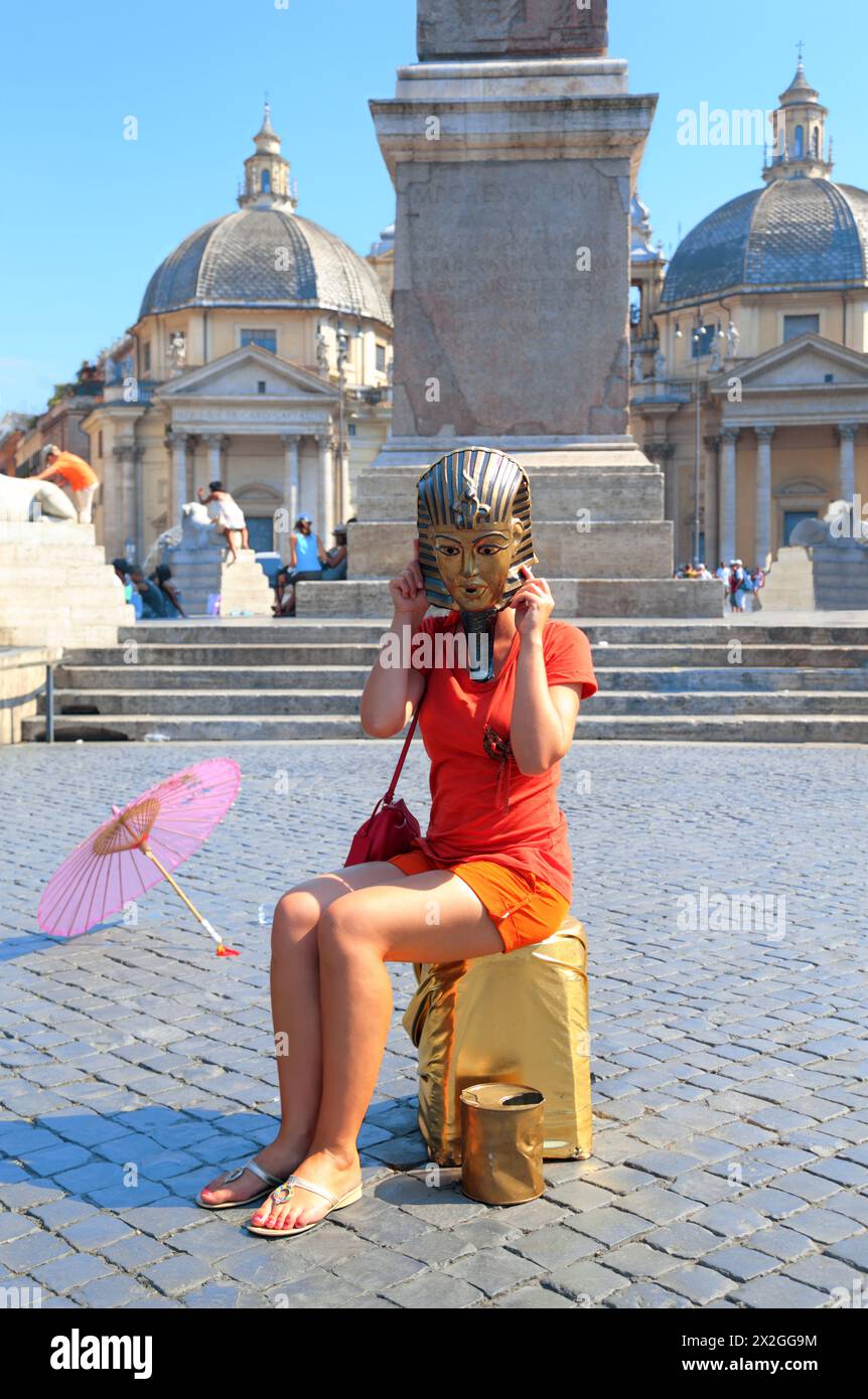 Junge Frau in Maske des ägyptischen Pharao und rosa Schirm auf der Piazza del Popolo in Rom, Italien Stockfoto