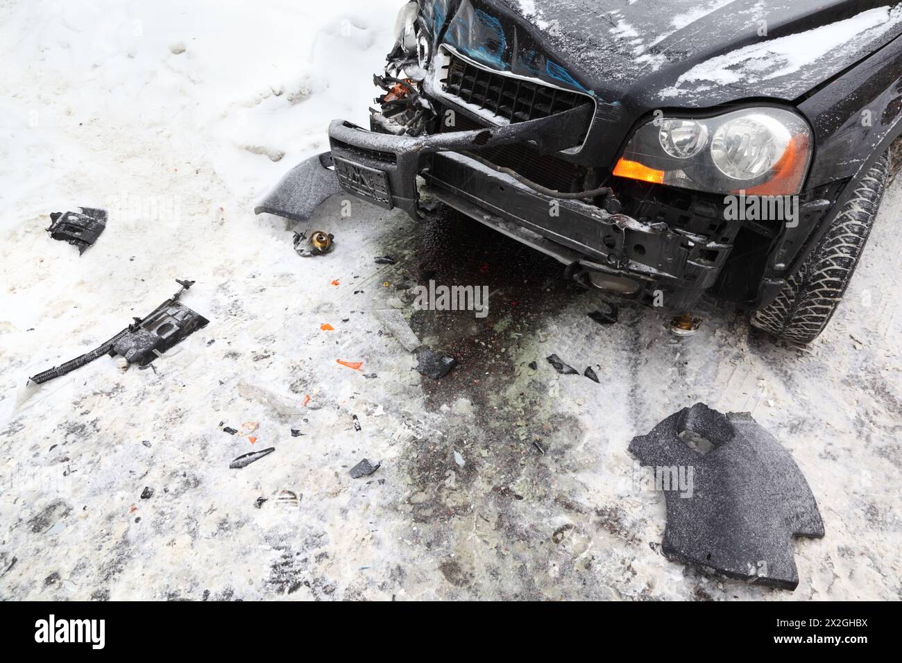 Kaputtes schwarzes Auto im Winter auf der Straße; Unfall; zerknitterte Motorhaube Stockfoto