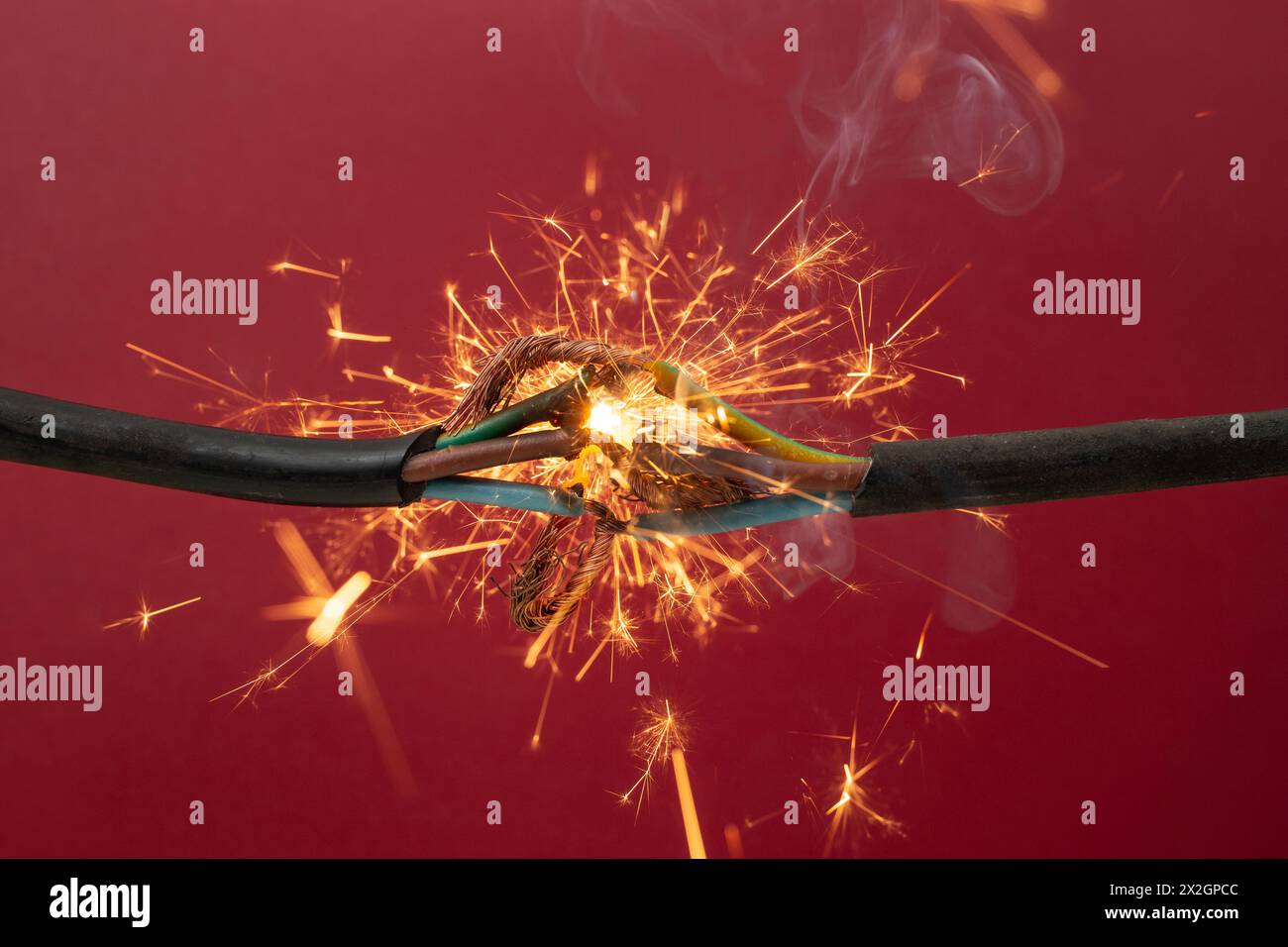 Funkenexplosion zwischen Elektrokabeln, auf rotem Hintergrund, Brandgefahrenkonzept, Weichfokus Stockfoto