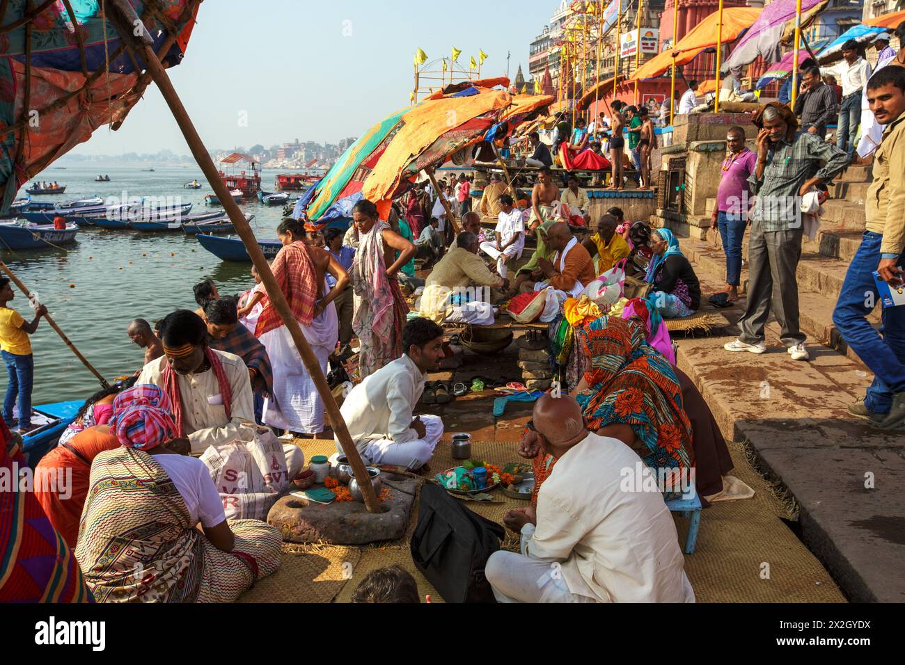 Hindupriester oder Pujaris unter großen Regenschirmen führen spirituelle Hindurituale für Pilger im Dashashwamedh Ghat in Varanasi, Indien, durch Stockfoto