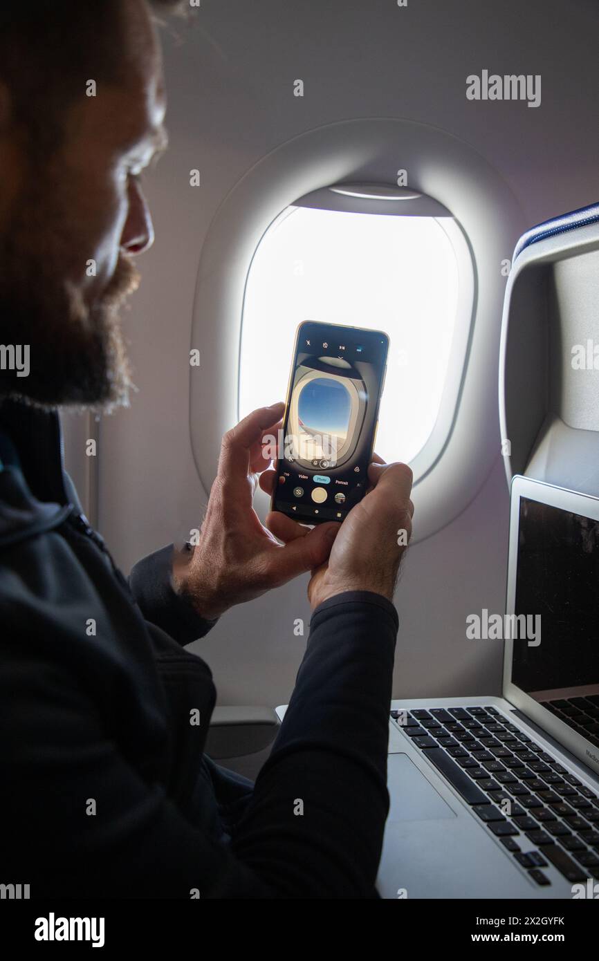 Ein Mann macht Fotos durch das Flugzeugfenster Stockfoto