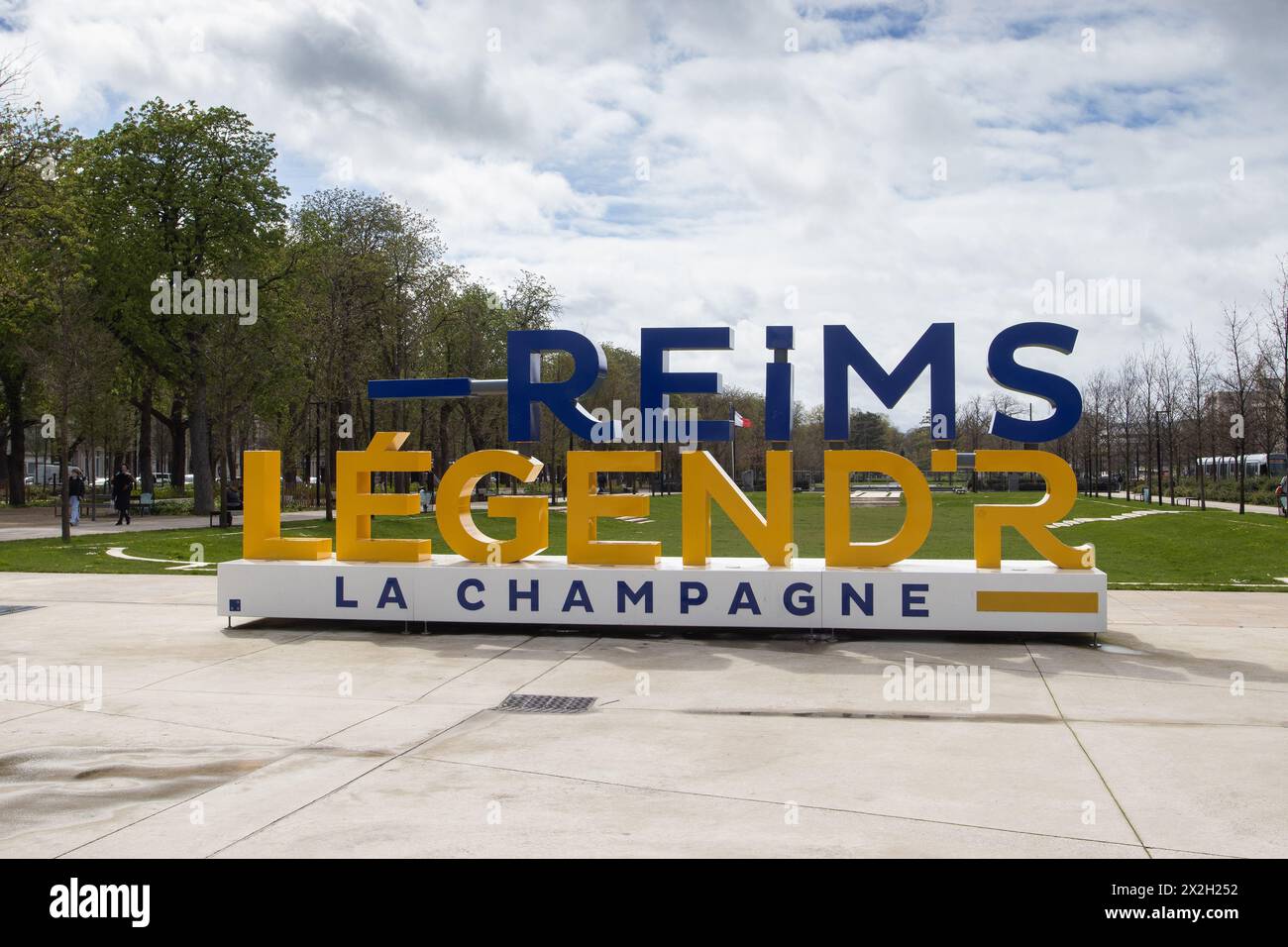 REIMS, FRANKREICH, 3. APRIL 2024: Straßenansicht der Stadt Reims und des Stadtparks mit dem Schild „Reims“ in großen blauen Buchstaben. Reims ist ein beliebter Tourist des Stockfoto