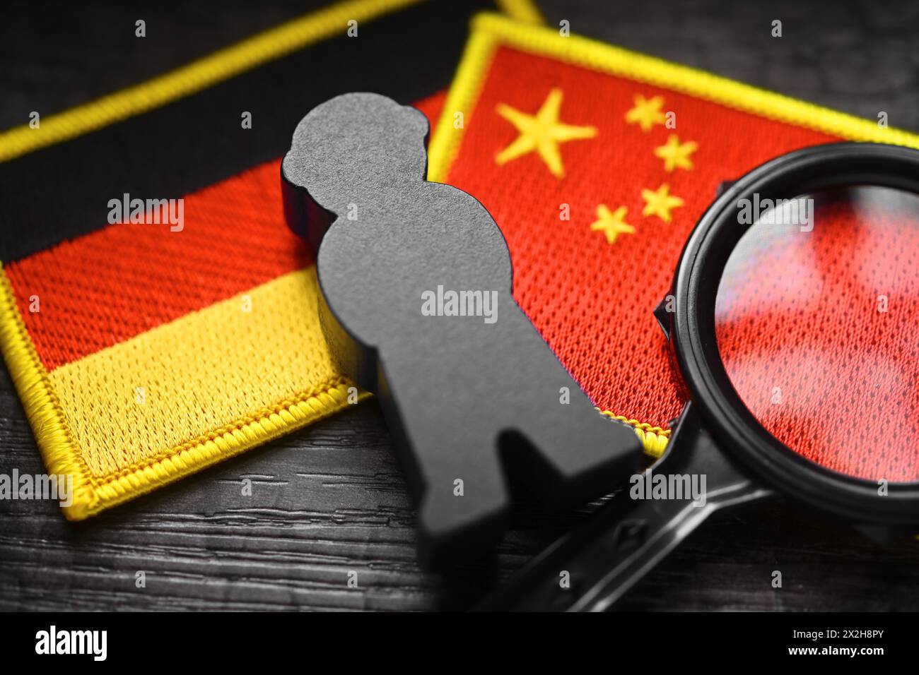 Schwarze Figur auf den Fahnen Deutschlands und Chinas, symbolisches Foto der chinesischen Spionage Stockfoto