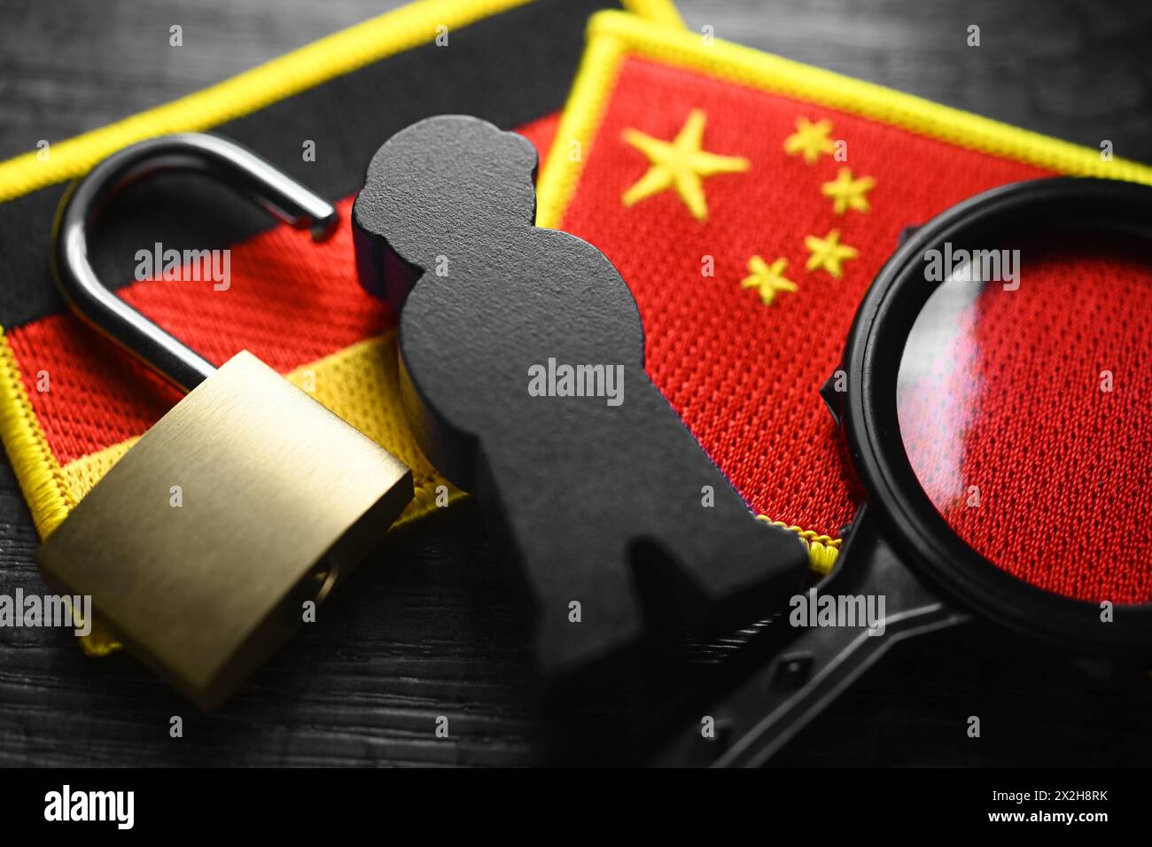 Schwarze Figur auf den Fahnen Deutschlands und Chinas, symbolisches Foto der chinesischen Spionage Stockfoto