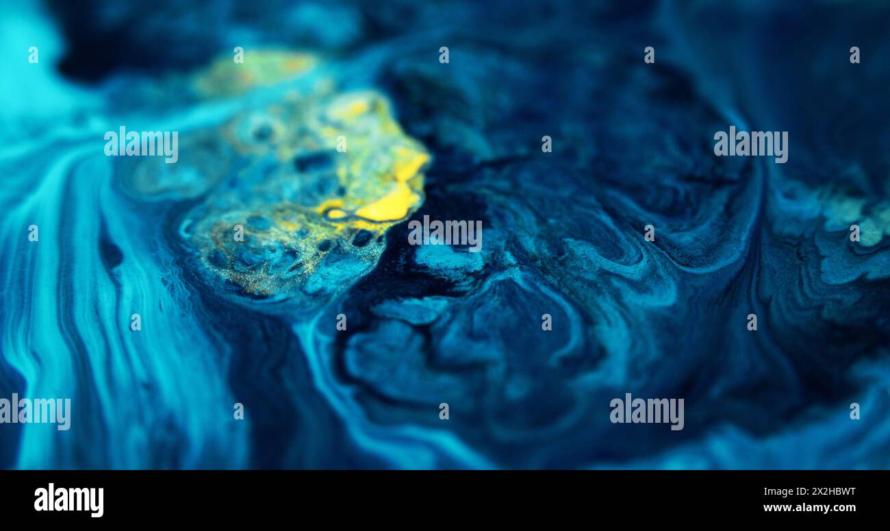 Farbfluss. Tropfen von Glitzerflüssigkeit. Defokussierte blaue gelbe Farbe metallisch schimmernde Goldpartikel Pigmentmischung Emulsion flüssige Tinte verschütten abstrakten Kunsthintergrund. Stockfoto