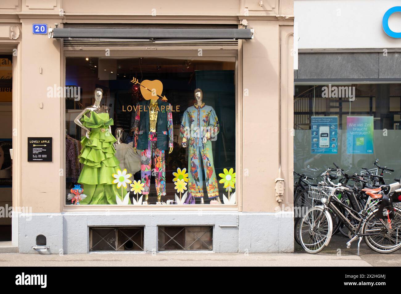 Basel, Schweiz - 18. April 2024: Stadtstraße mit Mode-Boutique schönes Apfelgeschäft und geparkten Fahrrädern Stockfoto