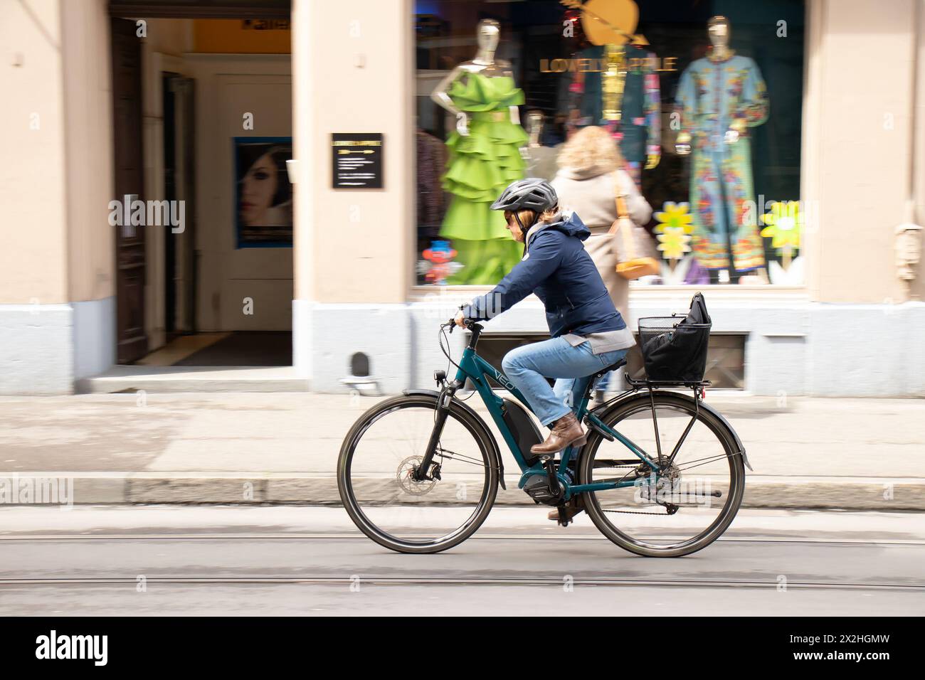 Basel, Schweiz - 18. April 2024: Eine Frau fährt Fahrrad auf der Stadtstraße Stockfoto