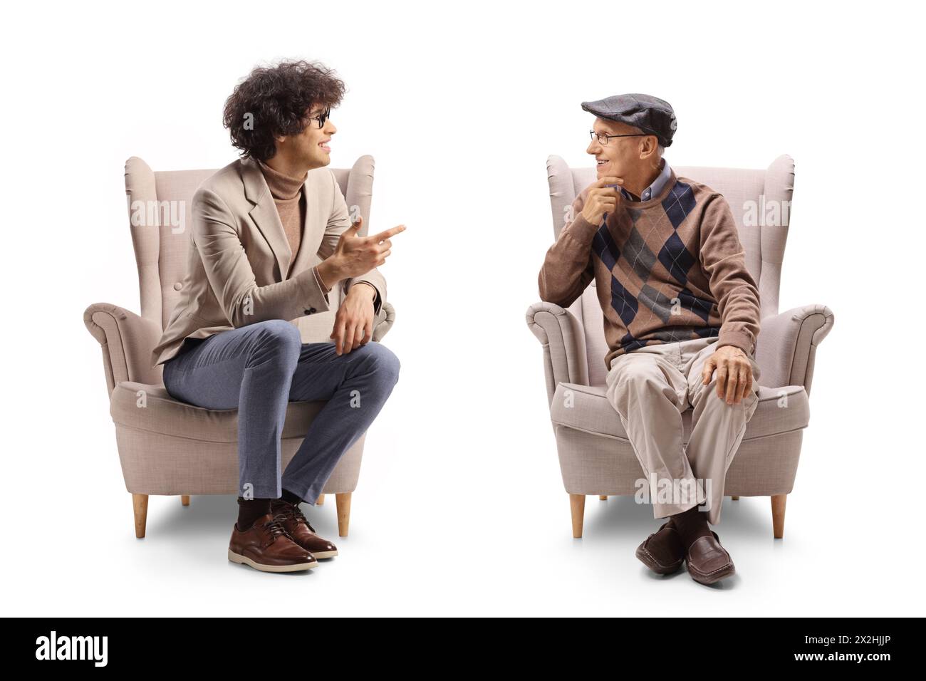Junger Mann mit lockigen Haaren und Brille, der in einem Sessel sitzt und mit einem älteren Mann spricht, isoliert auf weißem Hintergrund Stockfoto