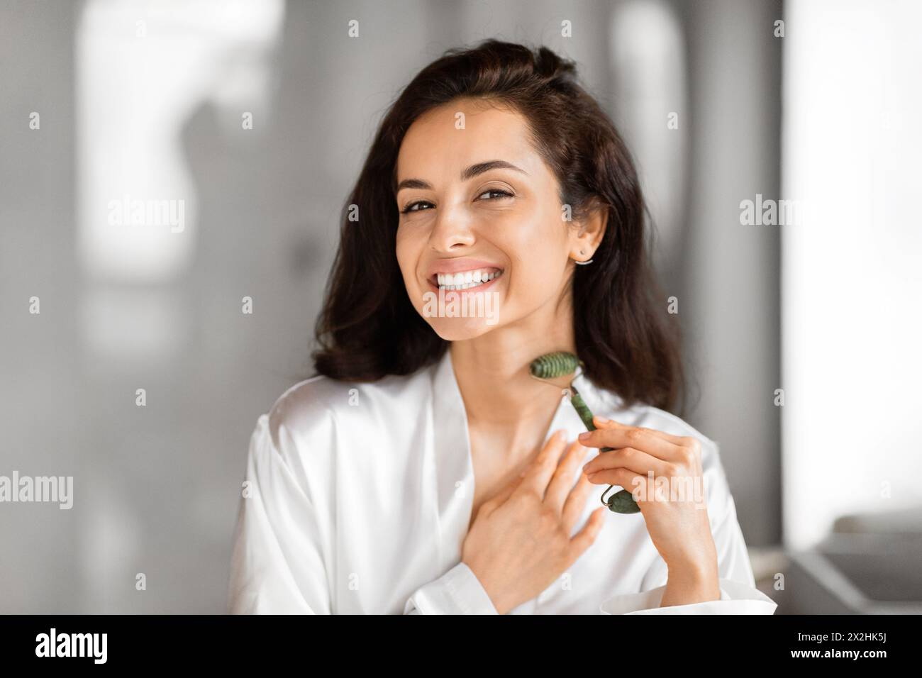 Lächelnde Frau, die Hautpflegeroutine im Badezimmer genießt Stockfoto