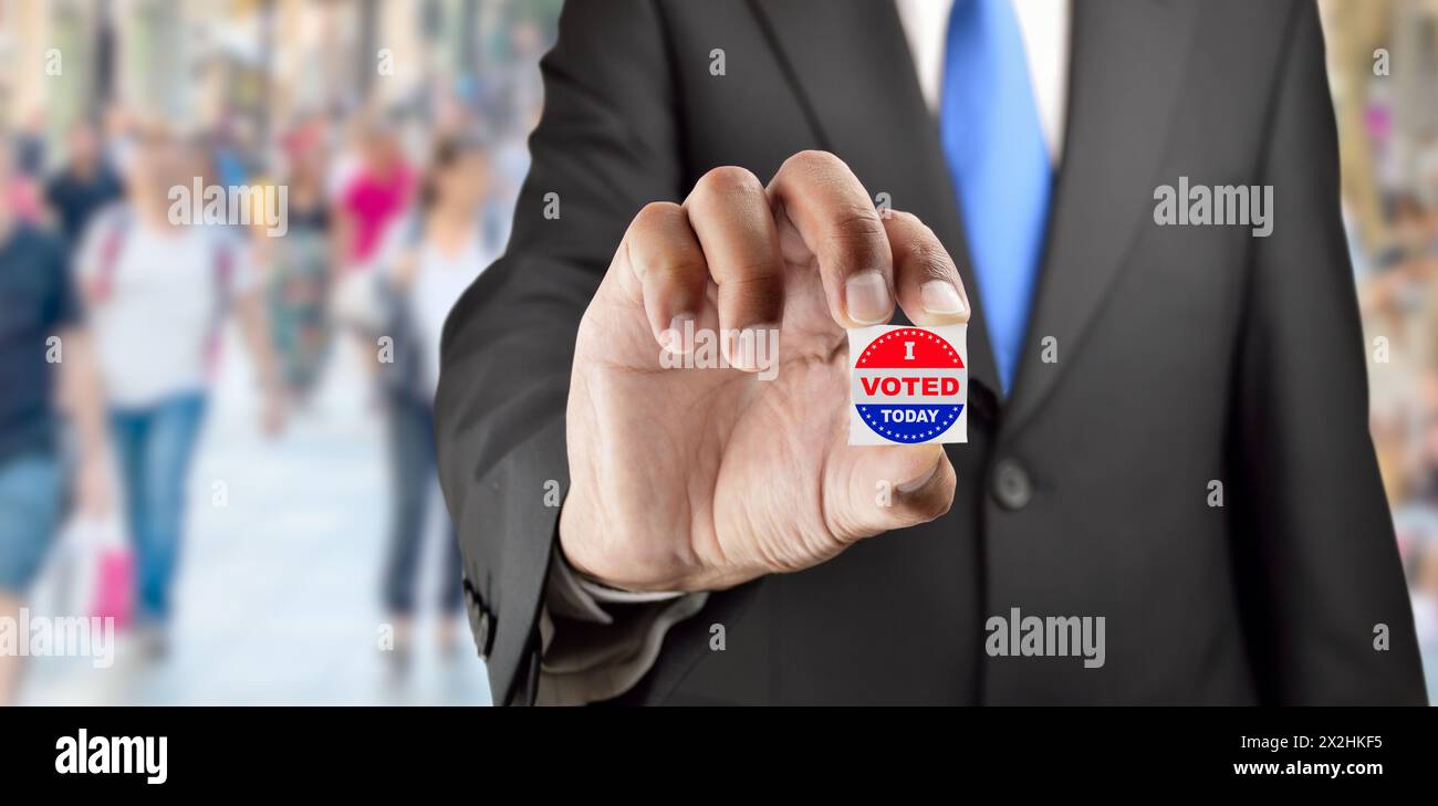 Ein Mann mit einem Wählknopf auf blauem Hintergrund für die Wahlen in den Vereinigten Staaten Stockfoto