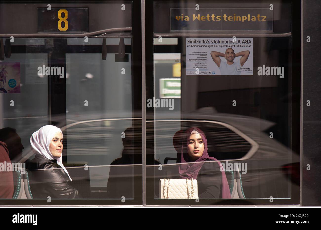 Basel, Schweiz - 18. April 2024: Junge muslimische Frauen im Hijab sitzen auf einem Fenstersitz, während sie in einer Straßenbahn Nr. 8 fahren Stockfoto