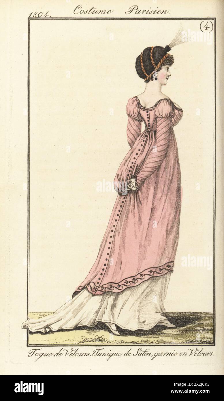 Frau mit Samtmütze, tiefgeschnittener Tunika aus rosa Satin mit Samtbesatz, weißem Bademantel und Hausschuhen. Velours-Toque. Tunique de Satin, Garnie en Velours. Platte 523 in der Pariser Ausgabe. Handkolorierter Kupferstich aus Pierre de la Messengere’s Journal des Dames et des Modes, Francfort sur le mein (Frankfurt) 1804. Nach Illustrationen von Carle Vernet, Jean-Francois Bosio, Dominique Bosio und Philibert Louis Debucourt. Stockfoto