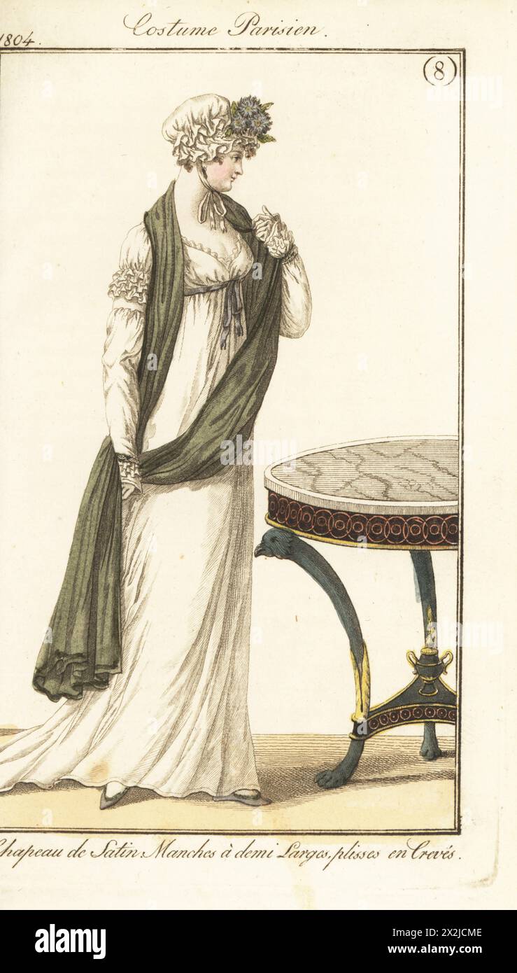 Frau in weißer Satin-Mütze mit einem Haufen Astern, Musselin-Gewand mit Plisseedärmeln, Seidenband und langem Schal, neben einem Tisch ein Dejeuner. Chapeau de Satin, Manches a demi Larges, plisses en creves. Pl. 527 in der Pariser Ausgabe. Handkolorierter Kupferstich aus Pierre de la Messengere’s Journal des Dames et des Modes, Francfort sur le mein (Frankfurt) 1804. Nach Illustrationen von Carle Vernet, Jean-Francois Bosio, Dominique Bosio und Philibert Louis Debucourt. Stockfoto