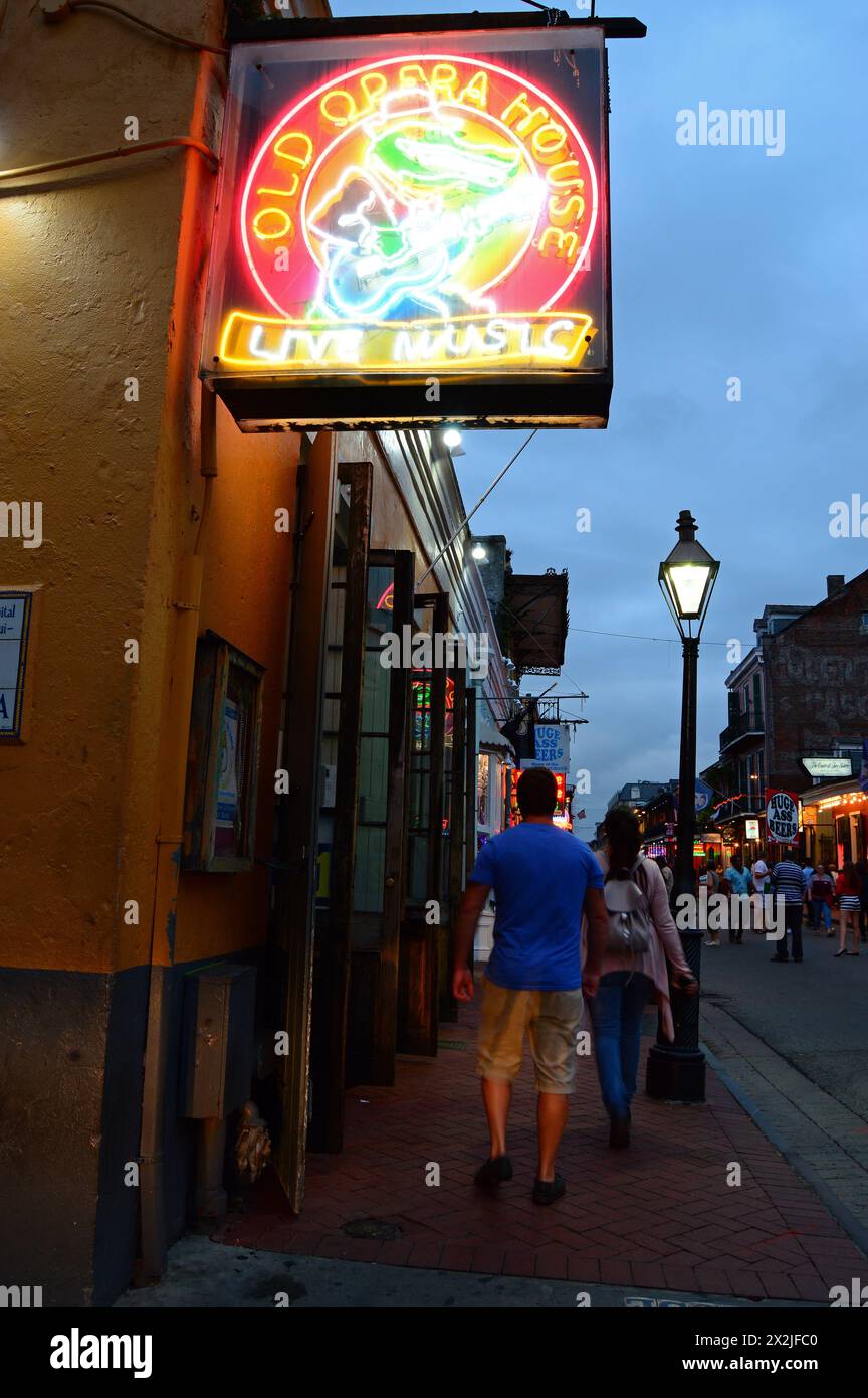 Besucher spazieren durch die Neonlichter und die Schilder der Nachtclubs und Cafés auf der Bourbon Street im New Orleans French Quarter Stockfoto