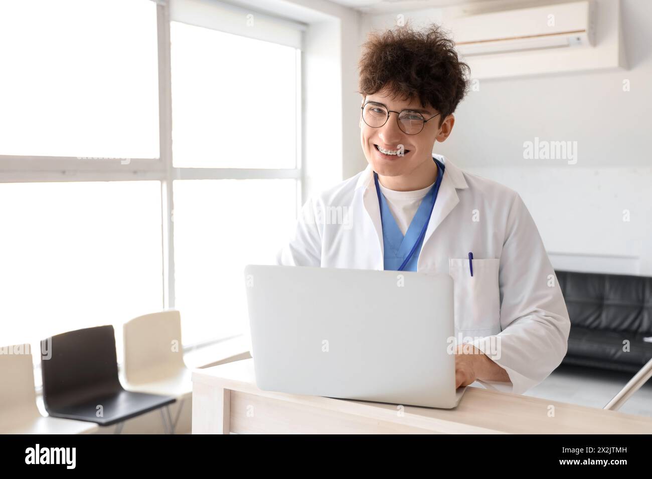 Männlicher Arzt mit Laptop an der Rezeption in der Klinik Stockfoto