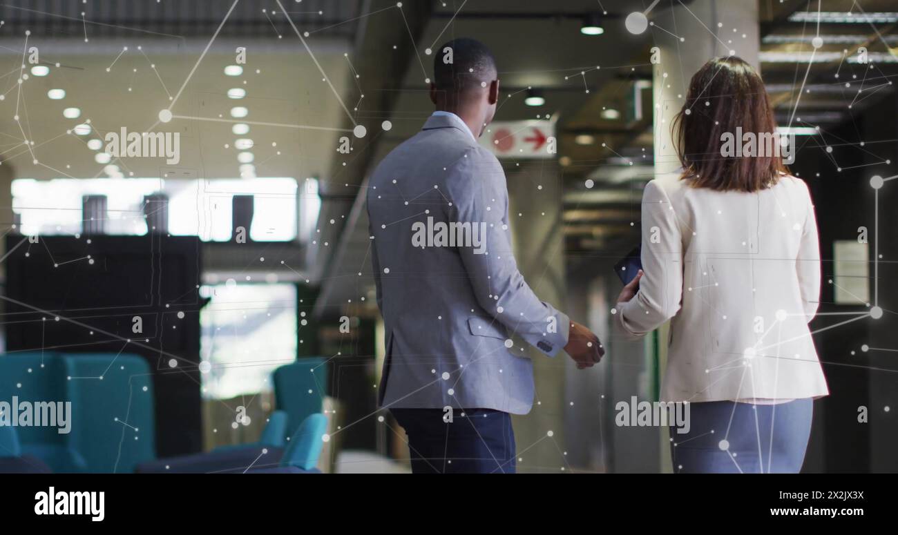 Bild der Datenverarbeitung über verschiedene männliche und weibliche Geschäftskollegen, die im Büro unterwegs sind Stockfoto