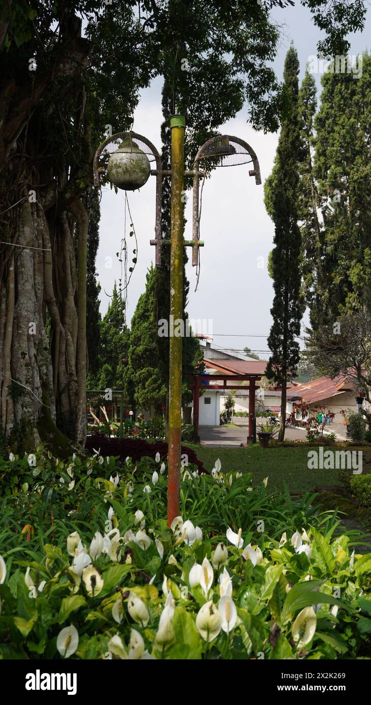 Eine Gartenlampe, die abgenutzt aussieht, eine Lampe fehlt und ein rostiger Stab in einer Touristengegend Stockfoto