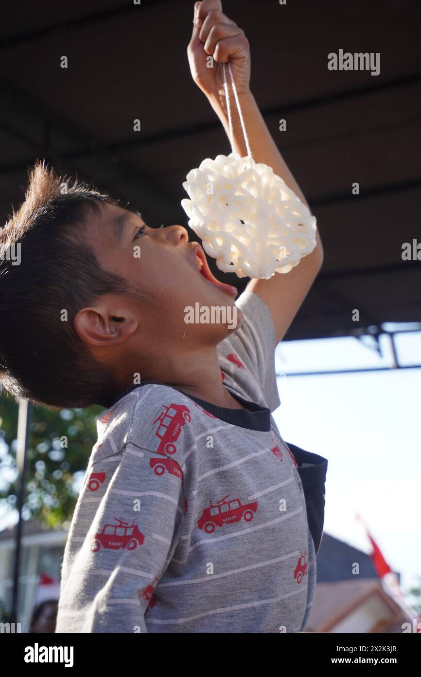 Kinder nehmen an einem Cracker-Ess-Wettbewerb zum Gedenken an Indonesiens Unabhängigkeitstag Teil Stockfoto