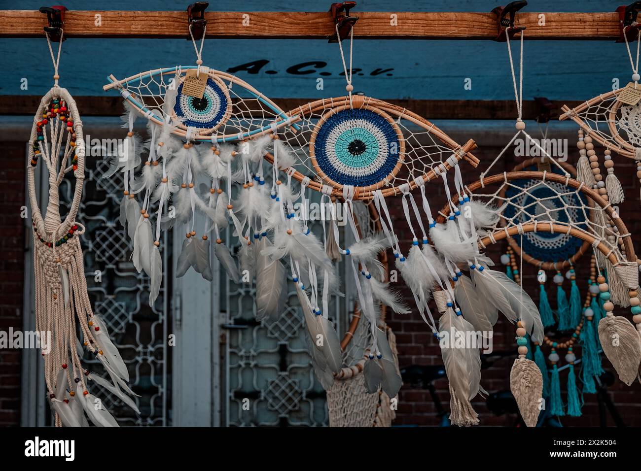 Verschiedene Traumfänger mit lebendigen Augenmustern und Federn hängen auf einem Marktplatz. Diese Handwerkskunst symbolisieren spirituelle Traditionen und künstlerische Traditionen Stockfoto