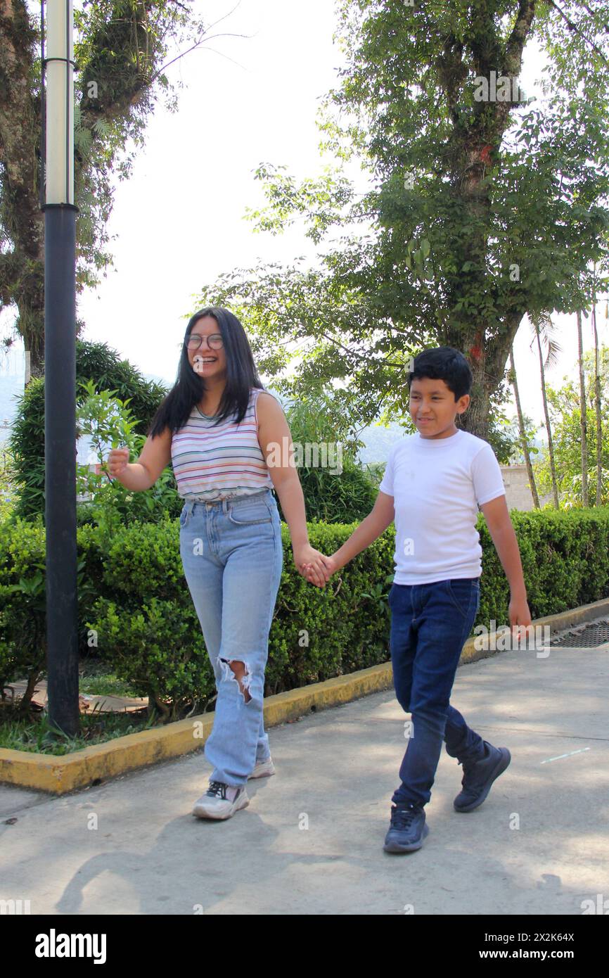 Die 16-jährige Schwester kümmert sich allein im Park um ihren 10-jährigen dunkelhäutigen Latino-Bruder, ohne dass sich ihre Eltern um sie kümmern Stockfoto