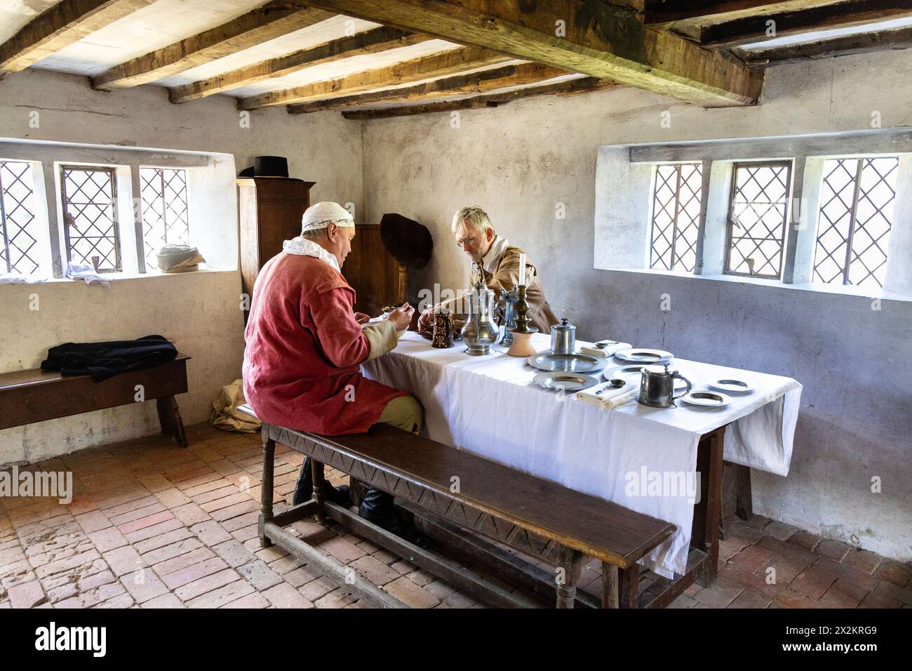 Zwei Bauern essen in einem Haus aus der Mitte des 17. Jahrhunderts aus Walderton, Weald & Downland Living Museum, West Sussex, England Stockfoto