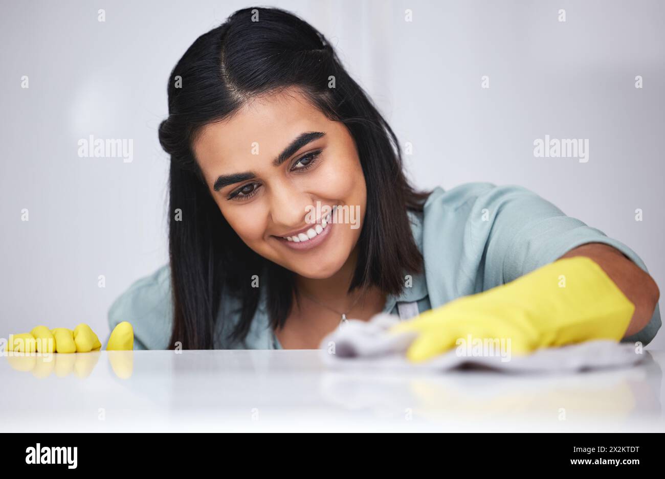 Indische Frau, glücklich oder sauber mit Sprühflasche für Tisch, Küchentisch oder schmutzige Möbel zu Hause. Lächeln, Zimmermädchen oder Hausmeister waschen unordentliche Oberflächen Stockfoto