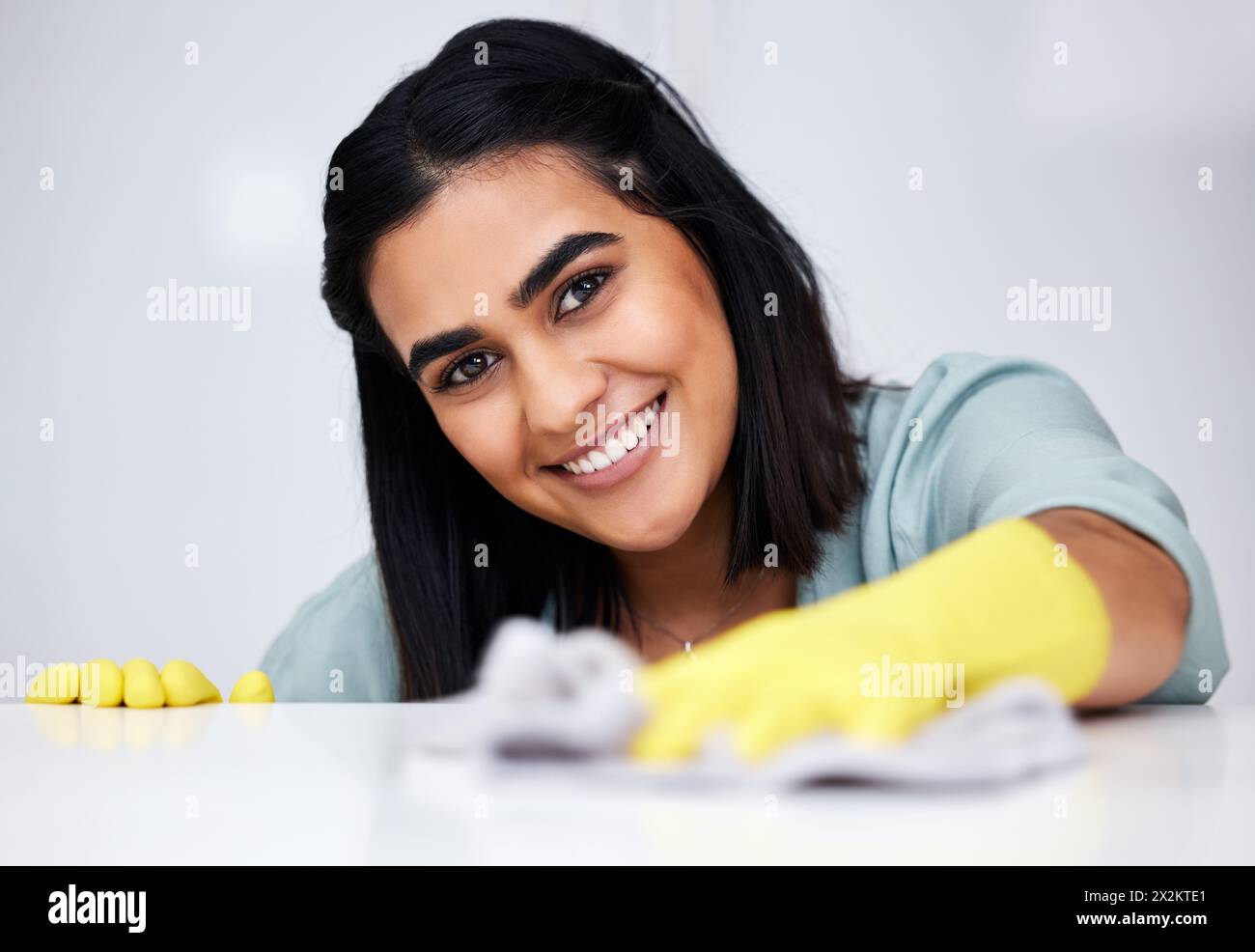 Indische Frau, Porträt oder Reiniger mit Tuch für Tisch, Küchentisch oder schmutzige Möbel zu Hause. Sicherheit, Zimmermädchen oder glücklicher Hausmeister waschen unordentlich Stockfoto