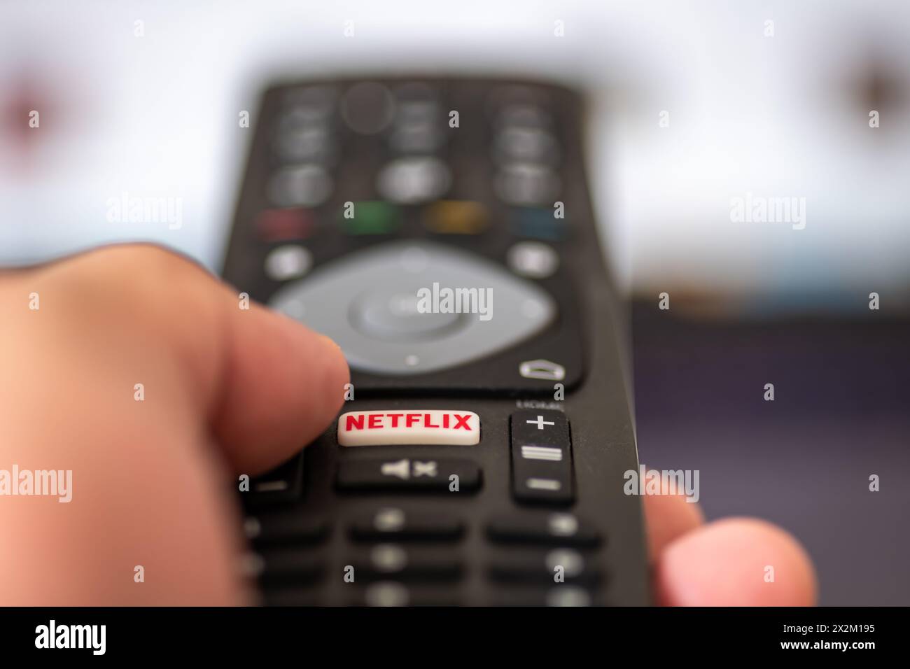 London. UK- 04.17.2024. Eine Hand, die eine Fernbedienung des Fernsehers hält, während der Finger die Netflix-Taste drückt. Stockfoto