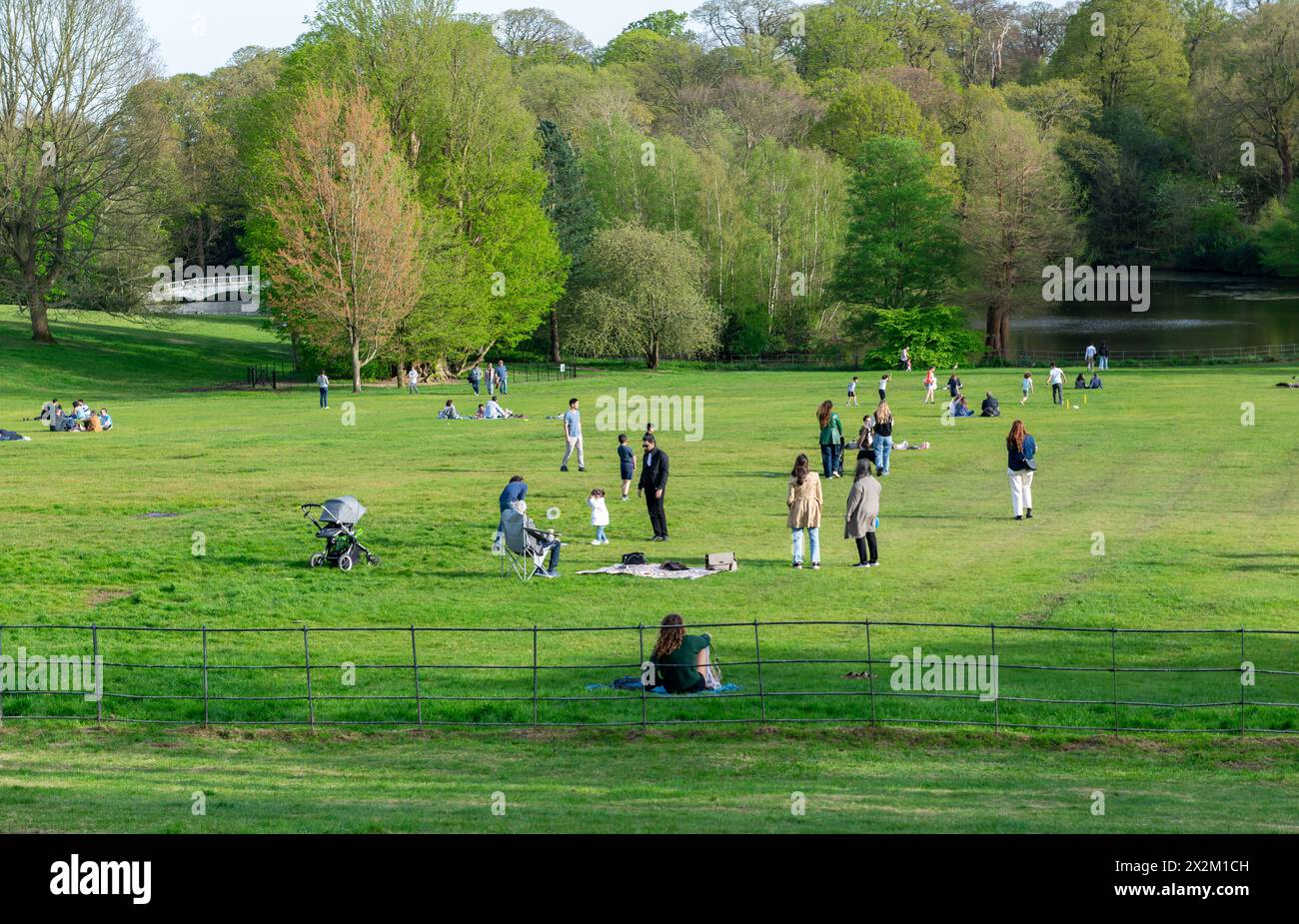 London. UK- 04.14.2023. Eine Menge von Menschen, die sich entspannen und einen Tag auf dem grünen Grasfeld eines Parks an einem schönen warmen, sonnigen Frühlingstag genießen. Stockfoto