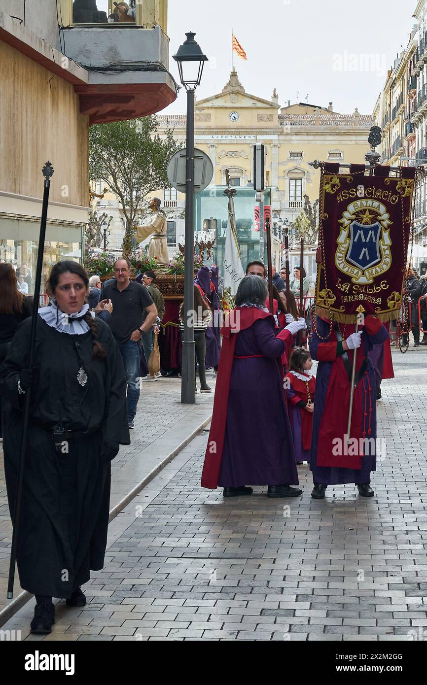 Tarragona, Spanien - 23. April 2024: Kulturelle Veranstaltung der Karwoche mit religiösen Persönlichkeiten und Gläubigen in zeremonieller Kleidung, die durch ein städtisches Gebiet ziehen. Stockfoto