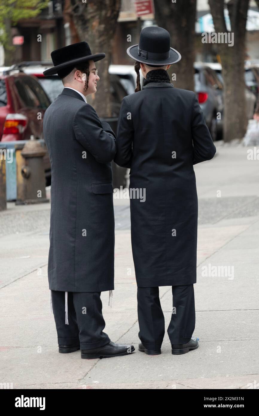 2 chassidische junge Männer mit langem Peyus-Gespräch an einer Straßenecke in Brooklyn, New York. Stockfoto