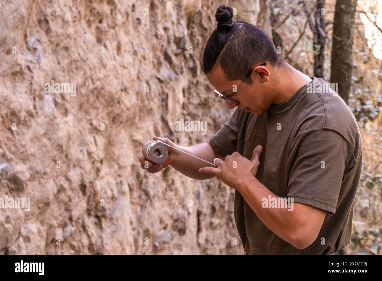 Junger Mann in lässiger Kleidung, der eine Rolle Klebeband untersucht, während er draußen steht Stockfoto