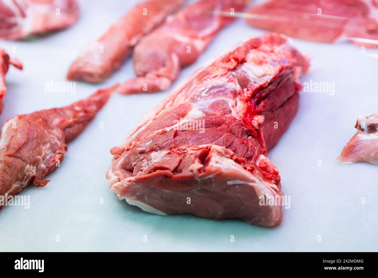 Verschiedene Stücke von rohem Kalbfleisch auf hellblauem Küchenpapier mit Texturen und Qualität für kulinarische Zubereitungen Stockfoto