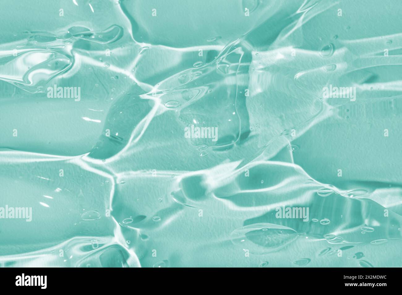 Ein Nahaufnahme-Bild, das die glänzenden, durchscheinenden Qualitäten einer aquatfarbenen Geltextur mit subtilen Lichtreflexionen zeigt Stockfoto