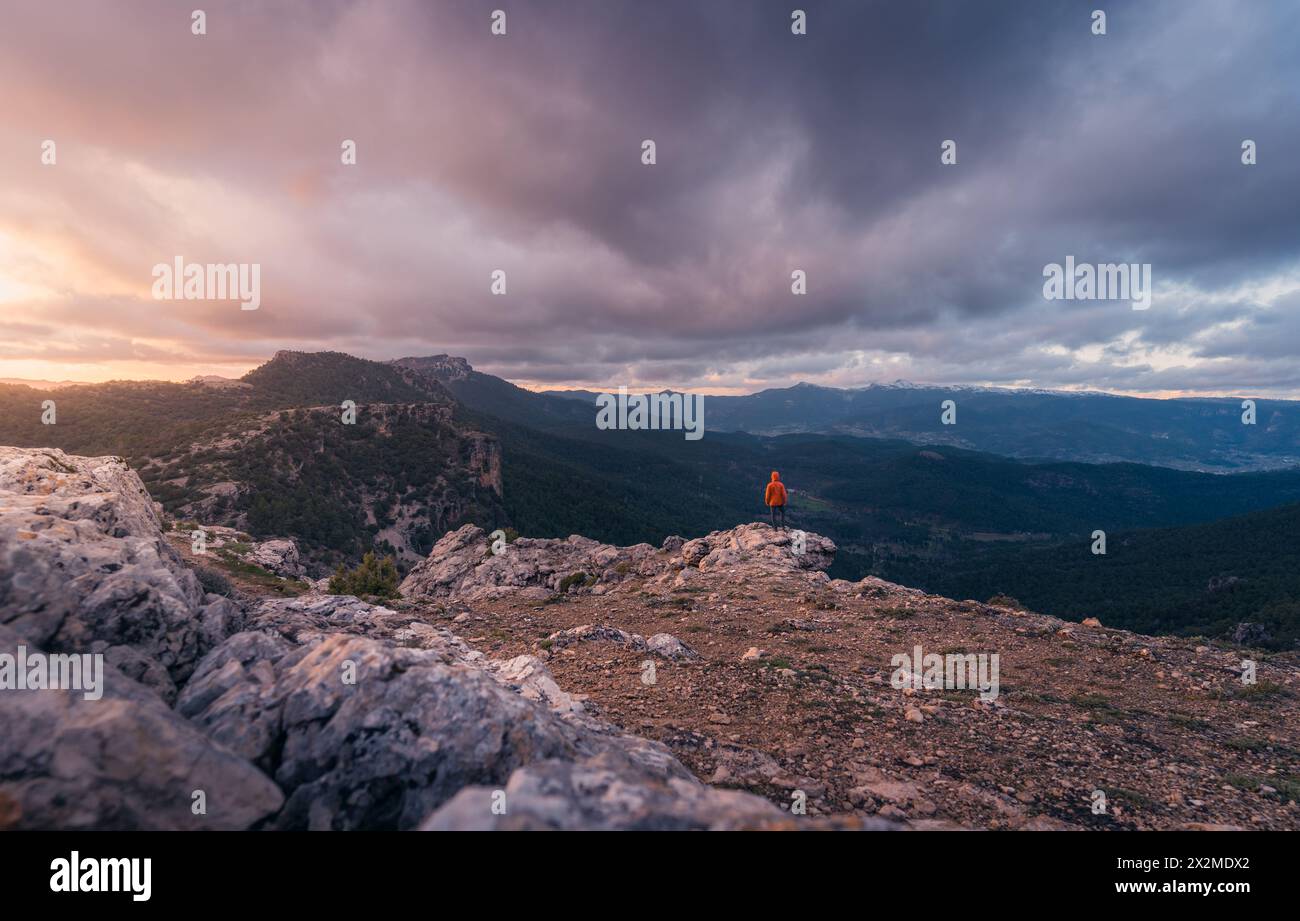 Eine einsame Figur steht auf einem zerklüfteten Gipfel und bestaunt einen wunderschönen Sonnenaufgang, der die wilde Landschaft von Kastilien-La Mancha beleuchtet und den Frieden symbolisiert Stockfoto