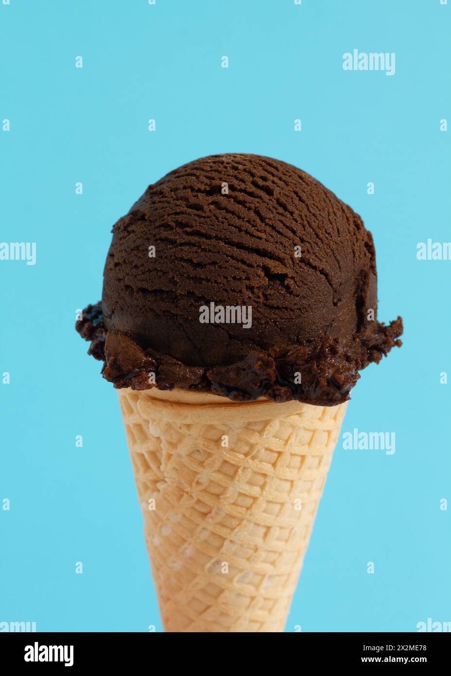 Eine Schaufel Schokoladeneis in einem Waffelkegel auf blauem Hintergrund Stockfoto