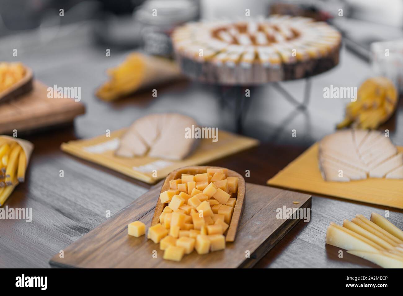 Eine Auswahl an Gourmet-Käsesorten, die kunstvoll auf rustikalen Holzbrettern angeordnet sind, perfekt für eine elegante Brautdusche oder einen Hochzeitsempfang Stockfoto