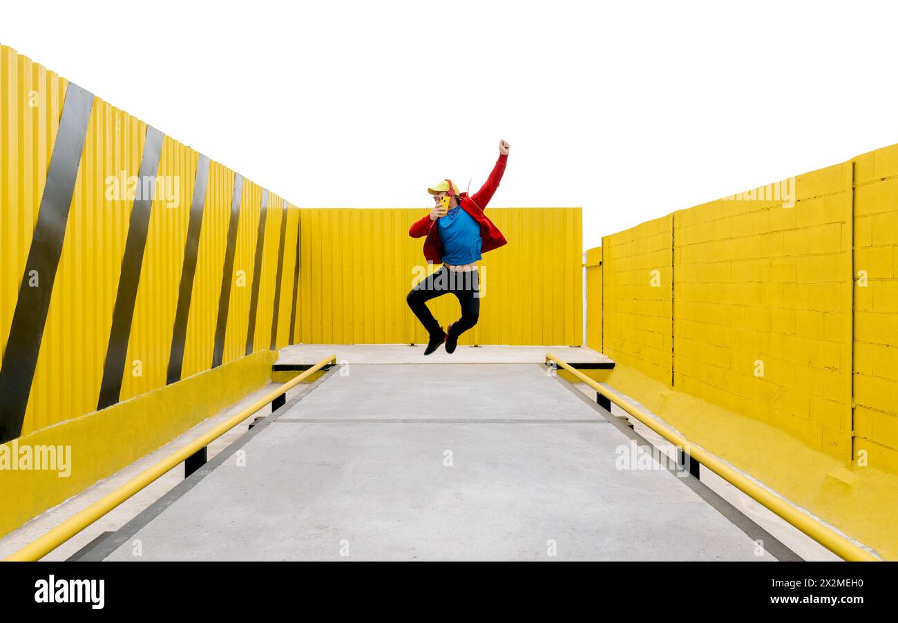 Person im dynamischen Mittelsprung vor einem auffälligen gelben geometrischen Hintergrund mit Kontraststreifen Stockfoto