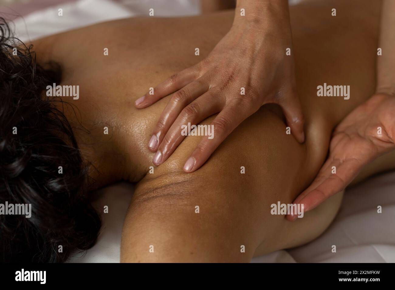 Lateinische Frau, die auf dem Rücken liegt und ayurveda-Massage erhält, Vorderhand einer Masseurin. Heilmassagekonzept Stockfoto