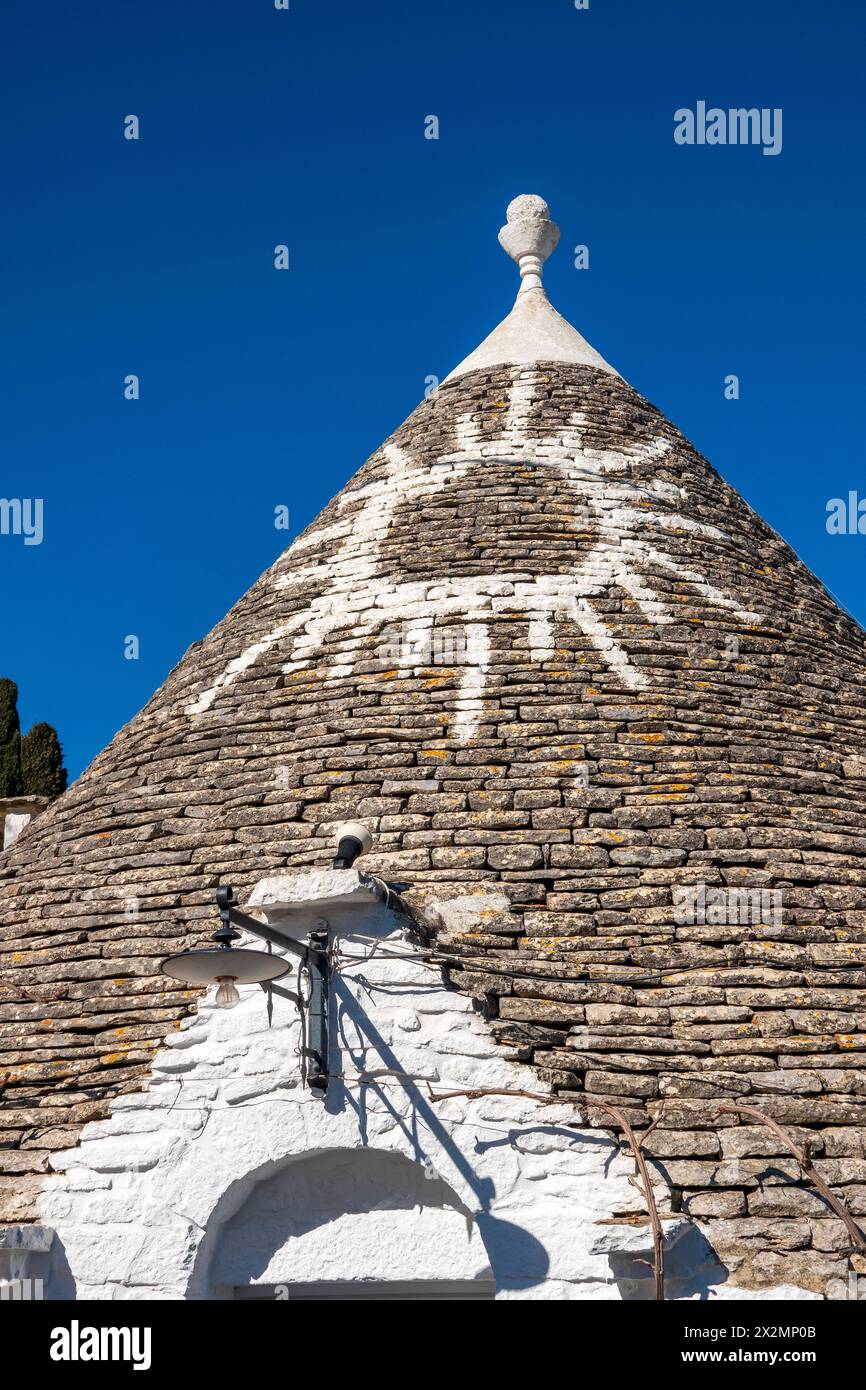 Weiß getünchte Symbole auf dem renovierten Steindach von A Trullo, Alberobello, Italien Stockfoto