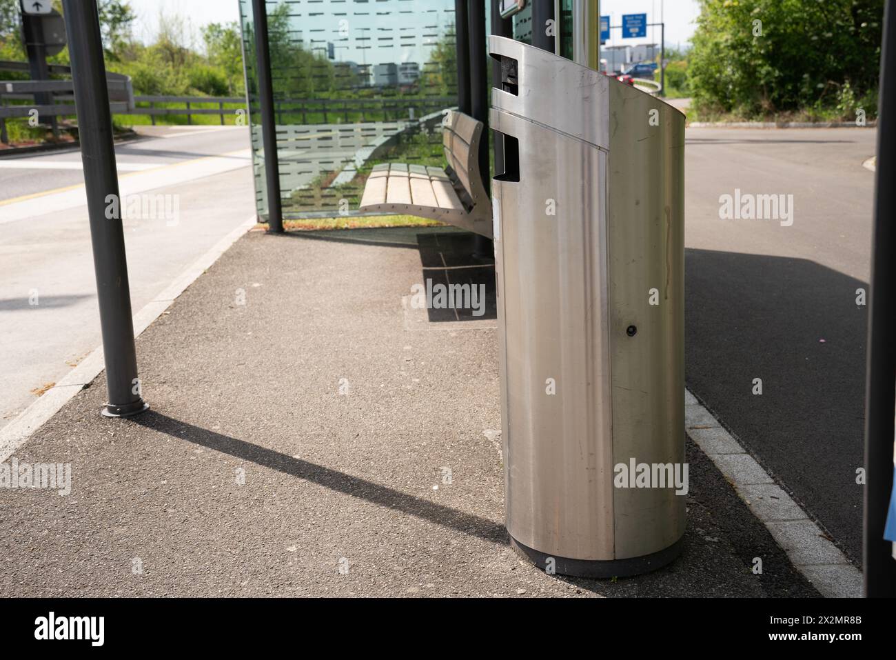 Moderner Mülleimer aus Edelstahl an einer Bushaltestelle mit Bank. Und Dach als Wetterschutz. Stockfoto