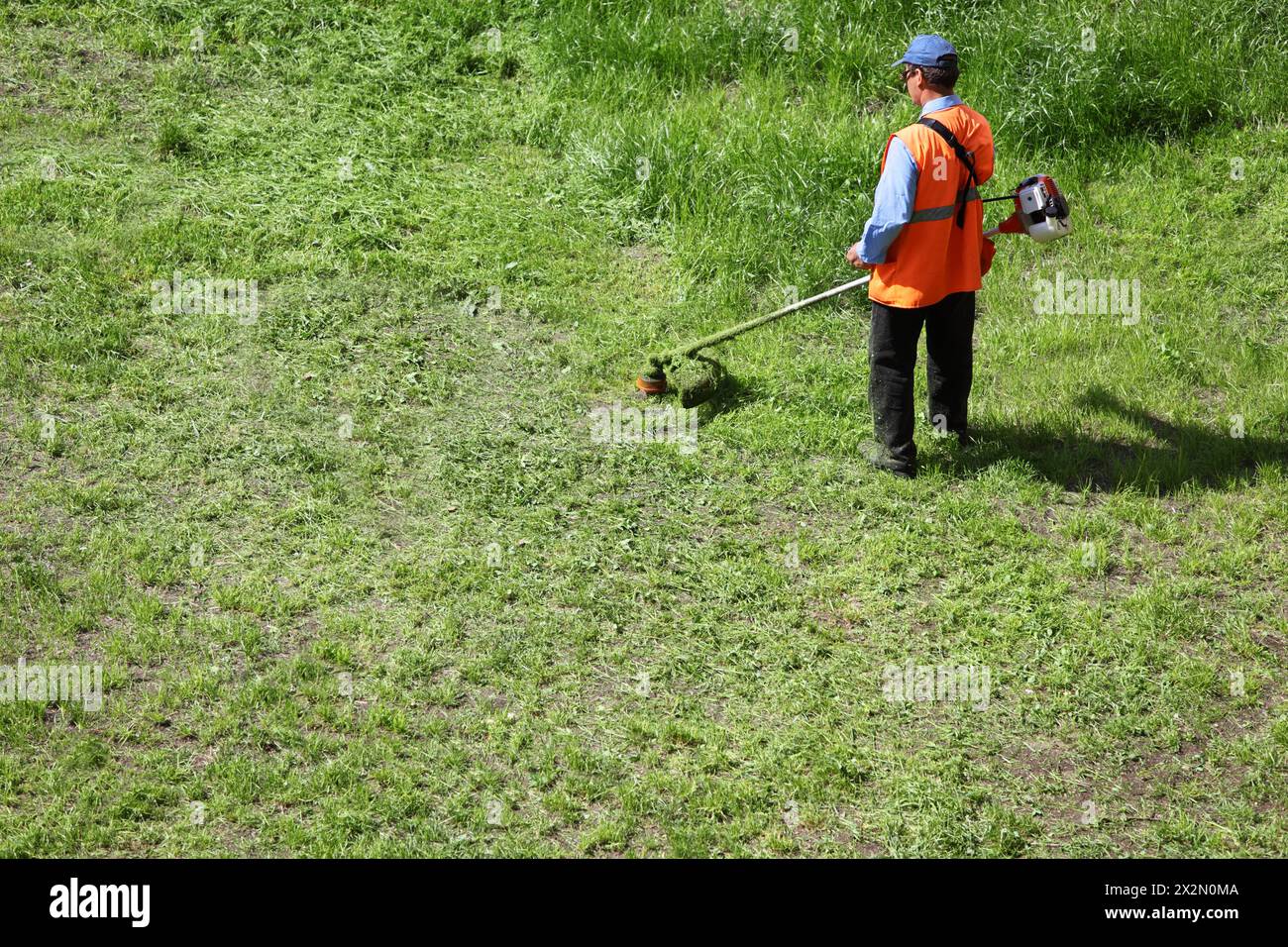 Mann Rasenmäher mit Häcksler Trimer bewegt Gras an sonnigen Sommertagen. Stockfoto
