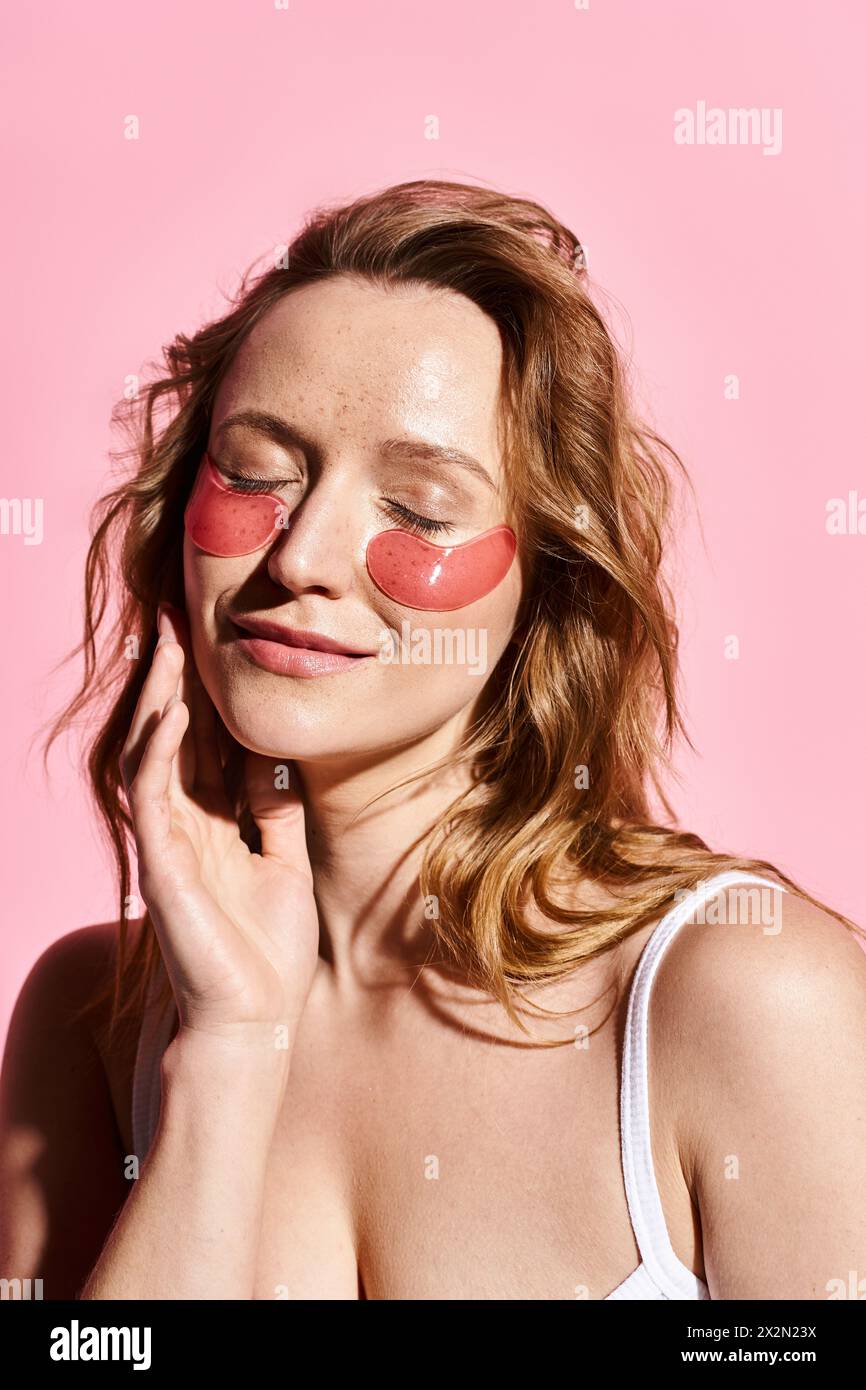 Eine natürliche Schönheitsfrau posiert aktiv mit einem roten Augenfleck auf ihrem Gesicht und trägt ein weißes Oberteil. Stockfoto