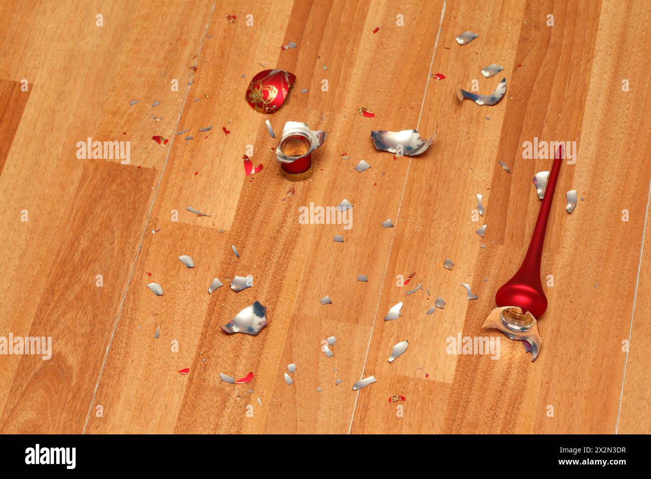 Schmiede von zerdrückter roter Weihnachtskugel auf sauberem Holzboden. Stockfoto
