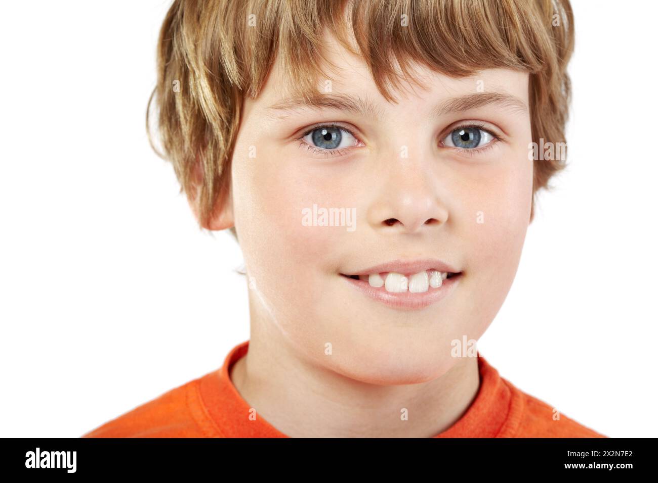 Close-up-Porträt eines lächelnden Jungen in orangefarbenem T-Shirt Stockfoto