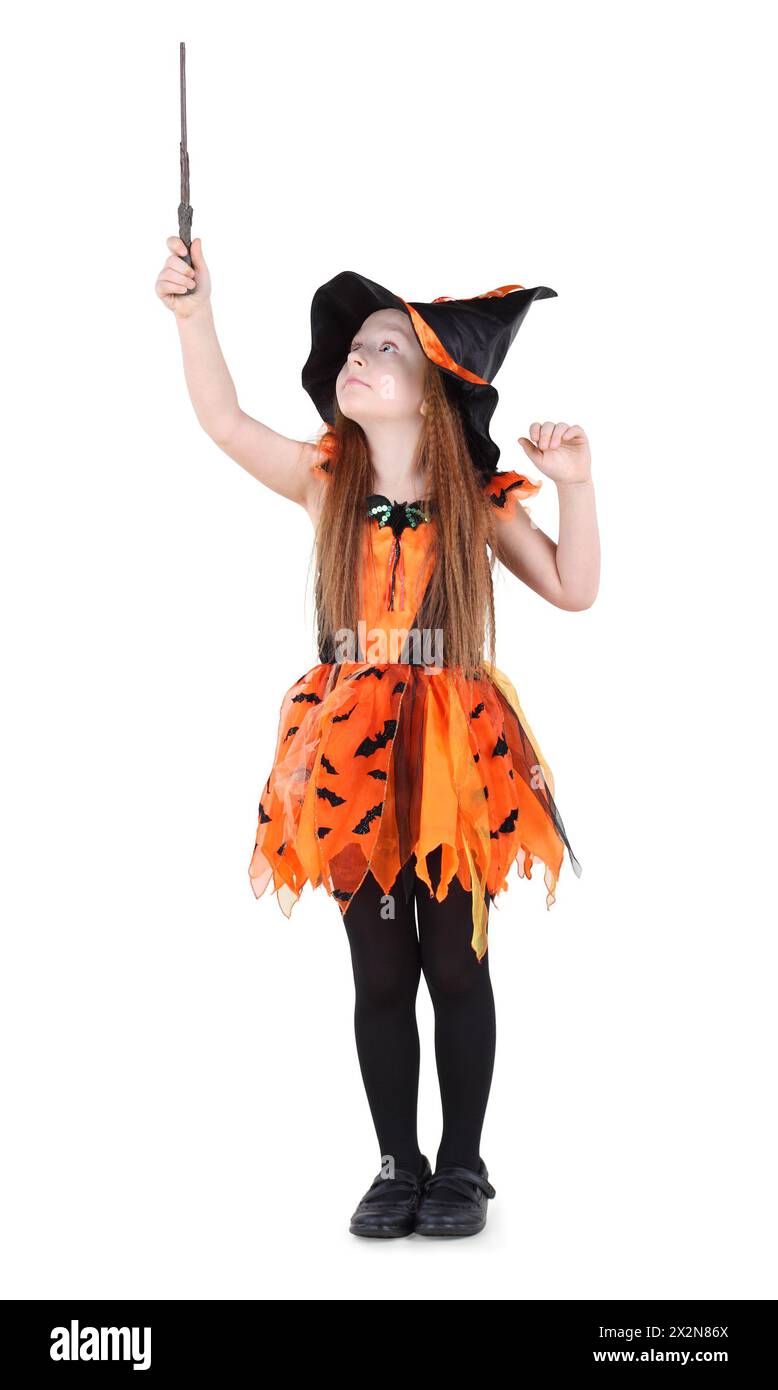 Kleines Mädchen in orangefarbenem Hexenkostüm für Halloween hält sich hoch und sieht den Zauberstab isoliert auf weißem Hintergrund. Stockfoto
